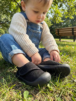 Baby mit Babyloom Puschies Barfußschuhe Schwarz auf dem Spielplatz
