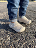 Baby trägt Babyloom Puschies Beige Barfußschuhe beim Spielen